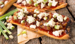 Pizza mit Schinkenwürfeln, Feta und Gurkensalat