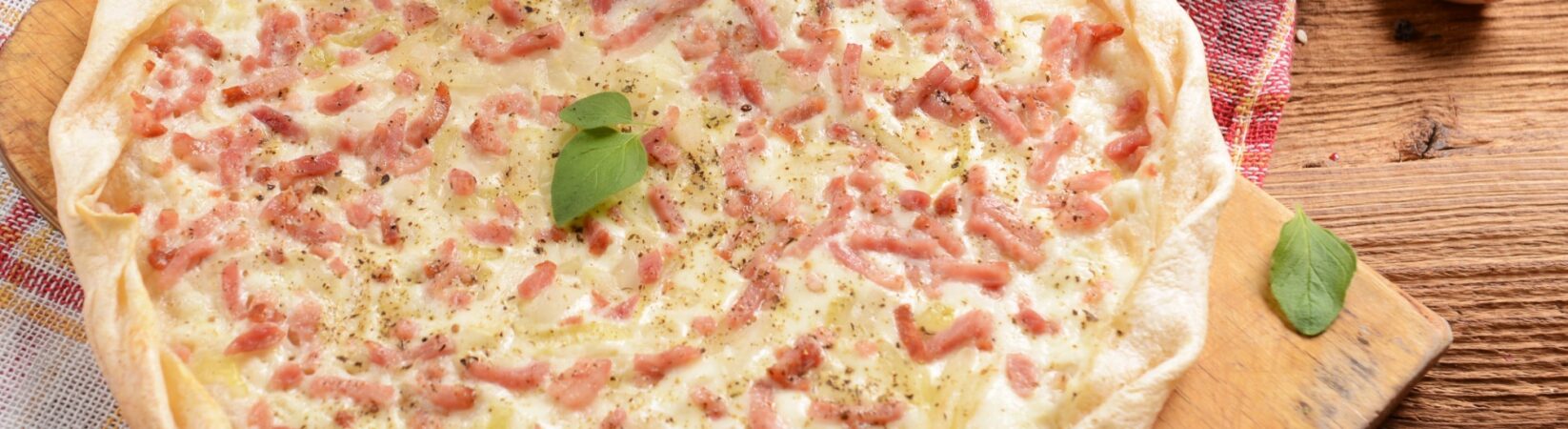 Flammkuchen mit Zwiebel- und Schinkenwürfeln und Tomatensalat