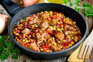 Gedünstetes Schweinefleisch mit Paprika, Mais, Möhren und Zwiebeln