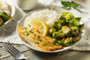 Paniertes Seebarschfilet mit geröstetem Rosenkohl und Reis