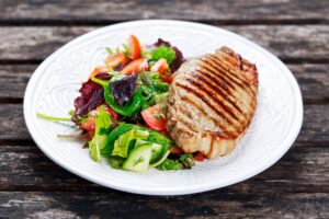 Schweinesteak mit Salat, Tomaten und Gurken